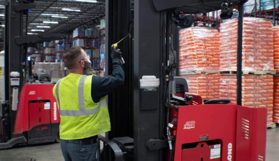 Technician lubricating forklift during maintenance